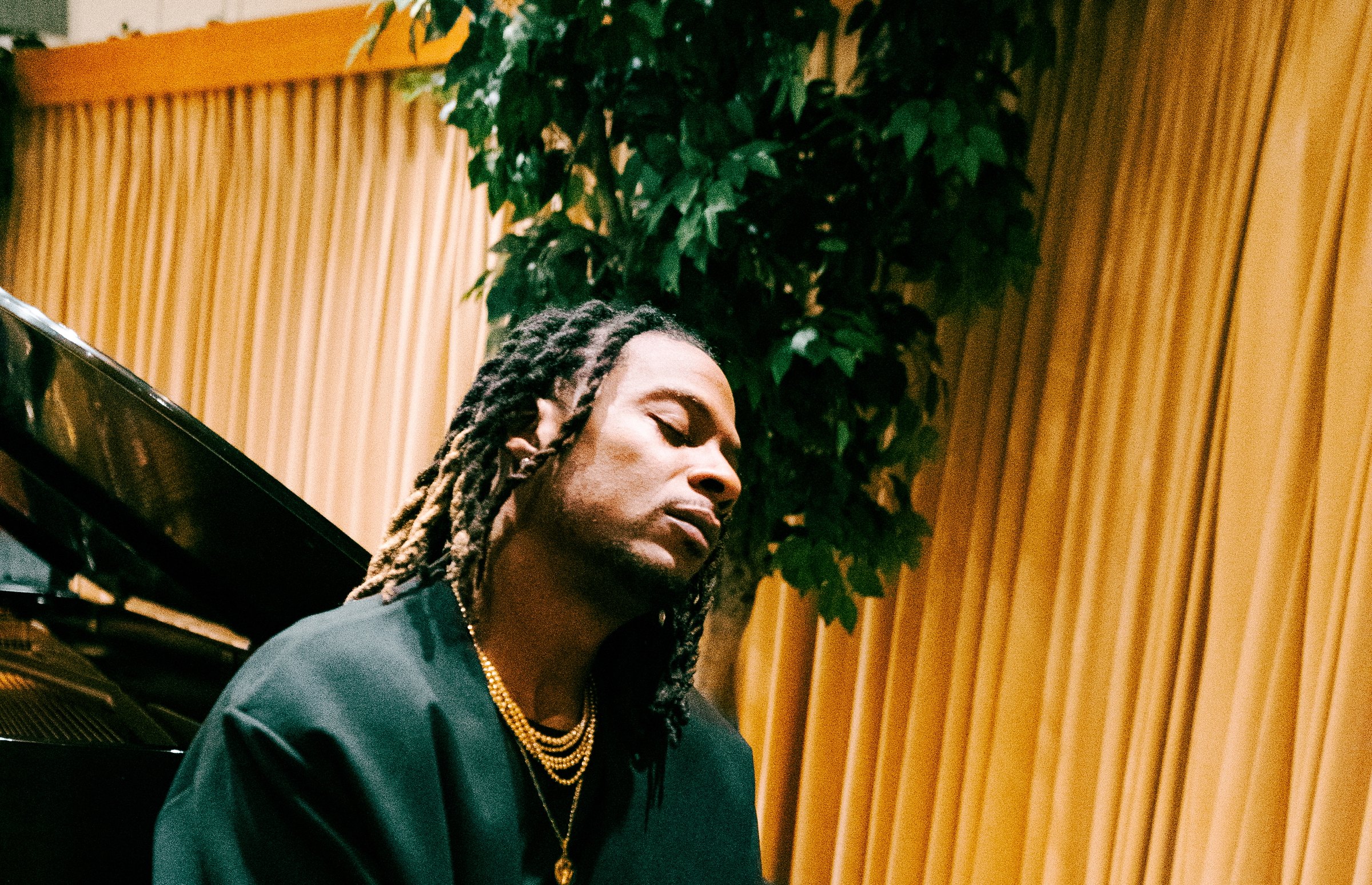 Kosine at the keys, eyes closed, in a warm studio